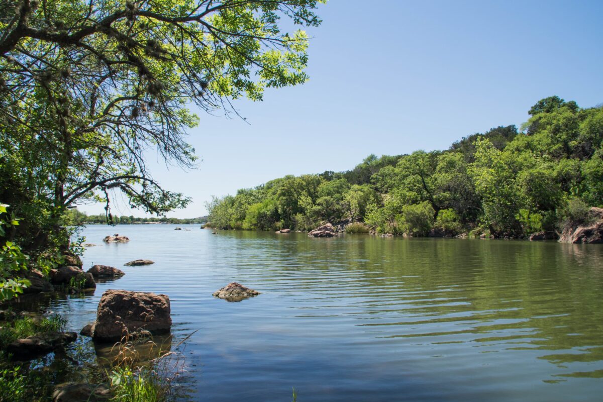 Swimmers and kayakers at Inks Lake State Park near Burnet Texas with pink granite shoreline